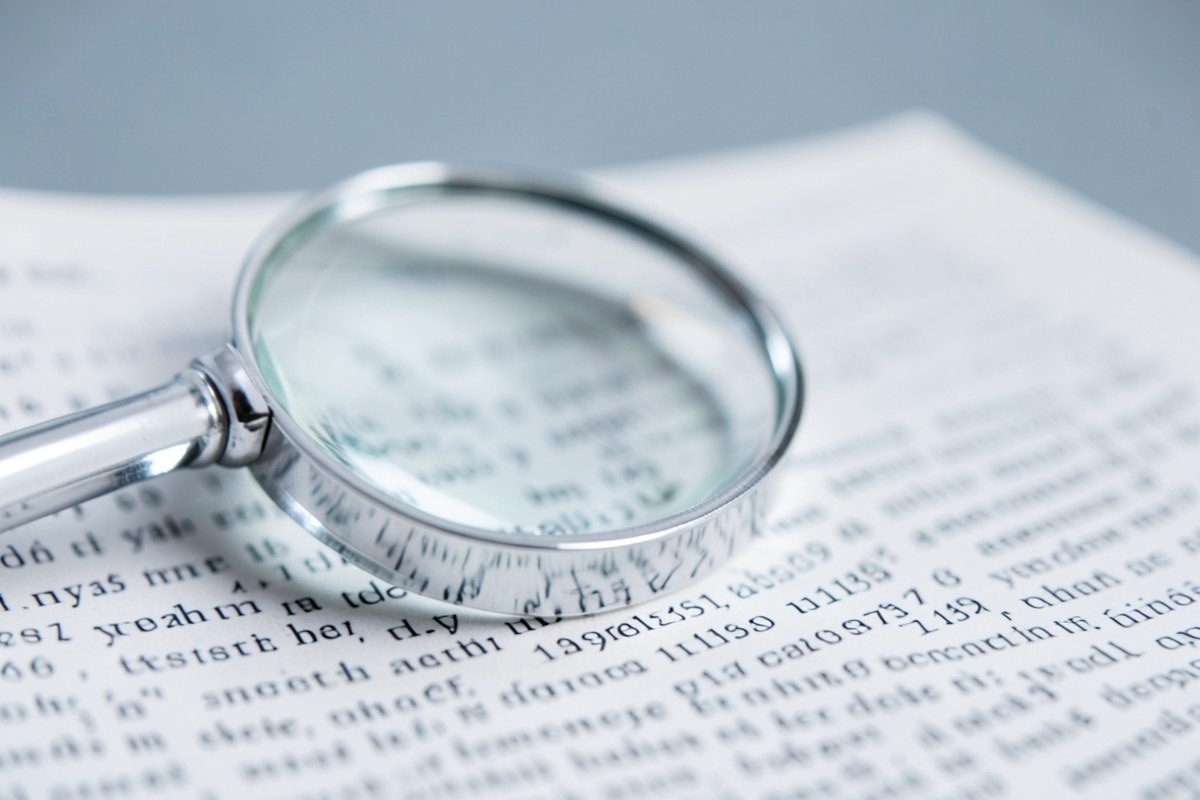 A conceptual image of a magnifying glass focusing on a piece of fine print, symbolizing careful review and important details.